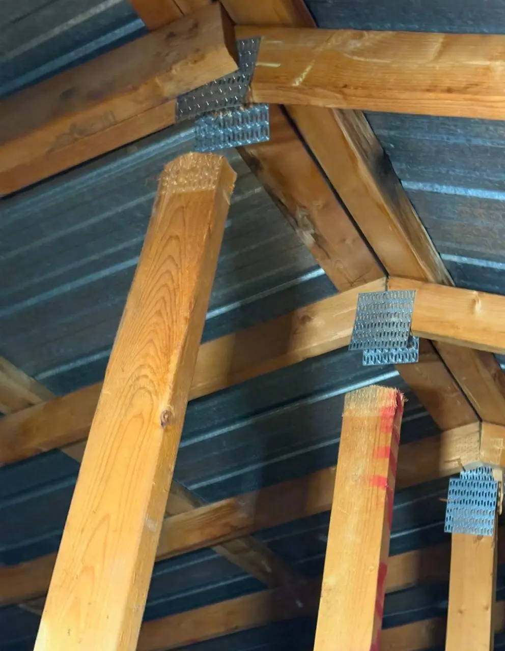 roof trusses detached from nail plates after wind damage to an older commercial building