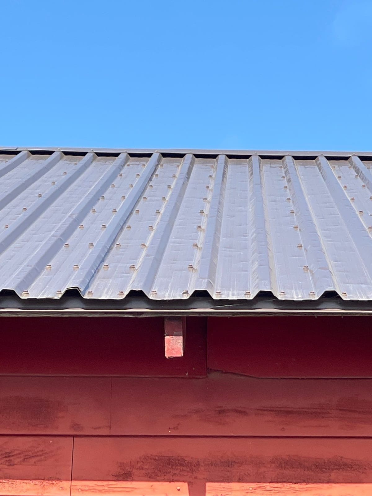 Viewing a sloped metal roof at a low angle where sunlight creates shadows/reflections across the panels