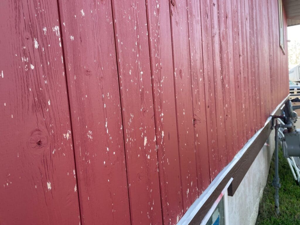 Paint damage to red wooden siding by hail hits