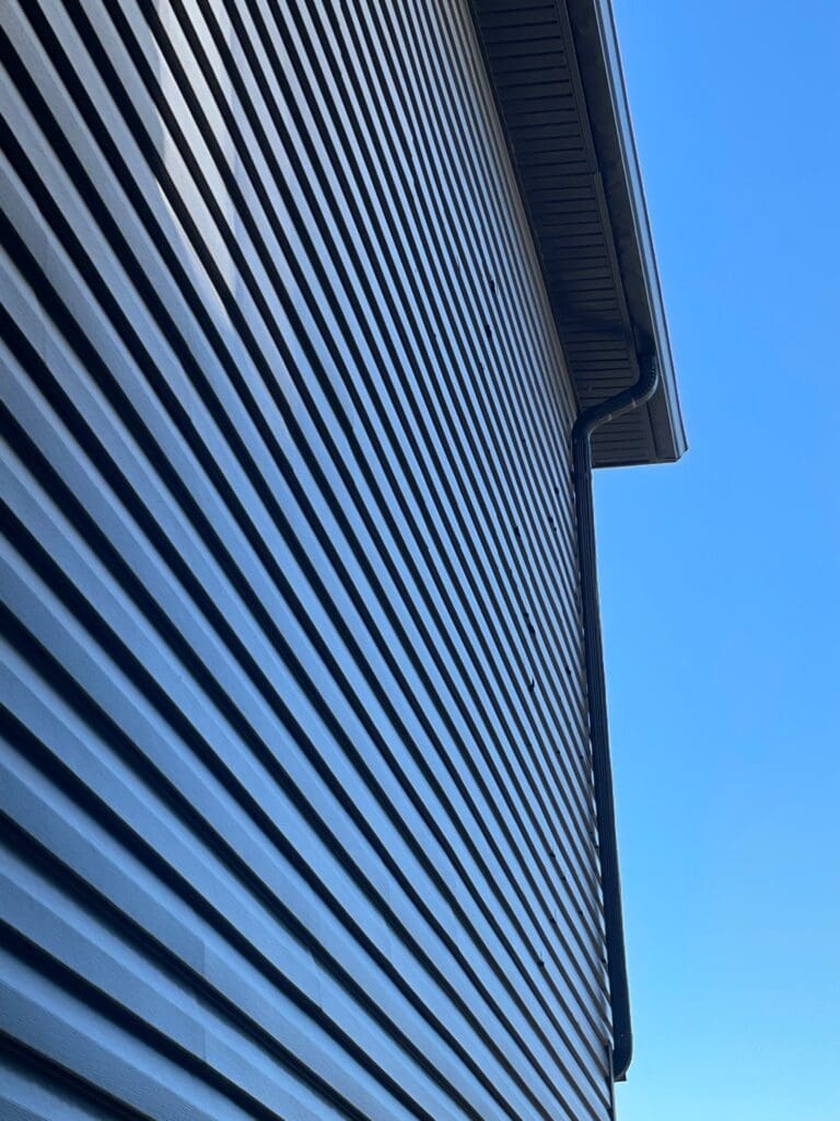 Close up vertical view of vinyl siding helps notice hidden or under panel hail hits