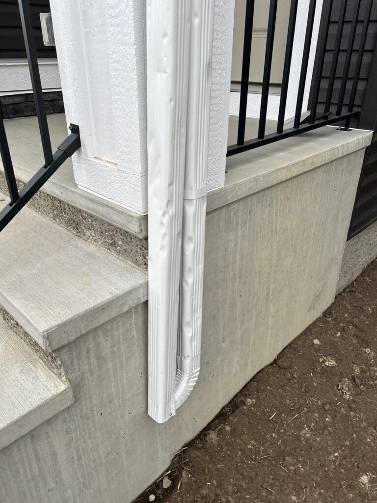 Spoon-shaped hail dents to white downpipe with extension