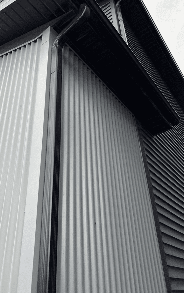 black-eaves-installed-contrast-corrogated-metal-sidingpanel black eaves installed at house corner with corrugated white metal panels
